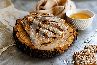 Healthy and nutritious diet bread with sesame and sunflower seeds on a thin crunchy malt base. Near natural bee honey and a wooden Stock Photo