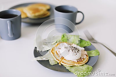 Healthy nutritious tasty breakfast. Pancakes, poached egg on ceramic plate and coffee cup. table setting. food photo. good morning Stock Photo