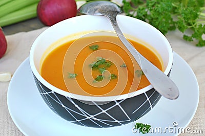 Healthy orange soup from pumpkin hokaido, green celery, garlic, onion and parsley in boxl with spoon on brown cloth and wooden Stock Photo