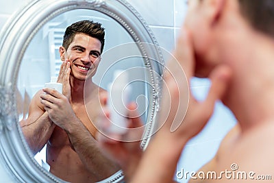 Healthy positive male treating sking with lotion Stock Photo