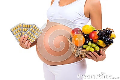 Healthy pregnancy: pills or fruit? Close-up of a pregnant belly Stock Photo