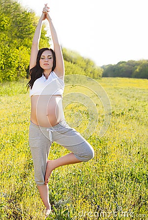 Healthy pregnant woman doing yoga in nature Stock Photo