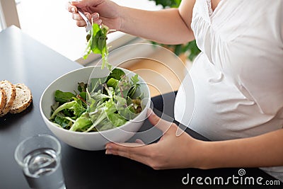 Pregnant woman eating a green salad at home Stock Photo