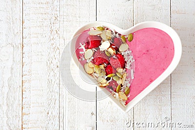 Raspberry smoothie in a heart bowl with superfoods over white wood. Stock Photo