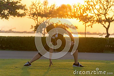 Healthy Runner asian woman athlete stretching legs for warming up before running in the park on sunset. Stock Photo