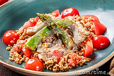 Healthy salad of barley porridge with asparagus, tomatoes and mushrooms on plate. Vegan food. Stock Photo