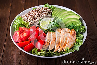 Healthy salad bowl with quinoa, tomatoes, chicken, avocado, lime and mixed greens, lettuce, parsley Stock Photo