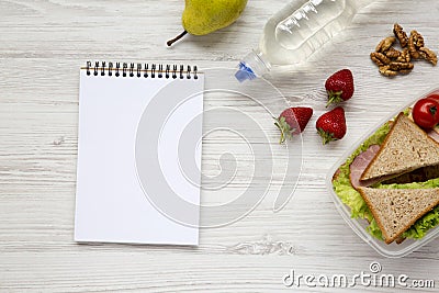 Healthy school lunch box with notebook on white wooden background, flat lay. From above. Top view. Stock Photo