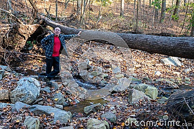 Healthy senior man by fallen tree on hiking trail Stock Photo