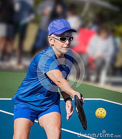 Healthy senior woman athlete hits a Pickleball volley close to the net Stock Photo