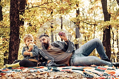 Healthy snack. Bite juicy apple. Family picnic. Hipster bearded dad with son spend time in forest. Brutal bearded man Stock Photo