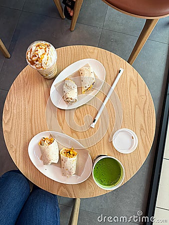 Healthy snack and drink on a wooden cafe table. Enjoy a delicious and nutritious break with wraps and vibrant beverages. Stock Photo