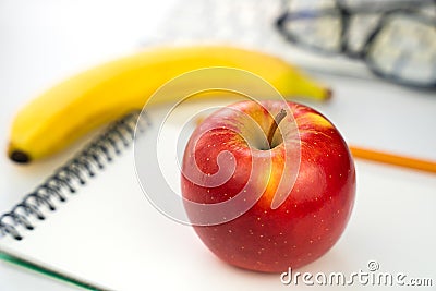 Healthy snack. A red apple on a blank notebook on the table. Back to school. Close-up. Selective focus Stock Photo