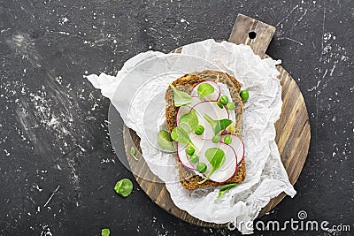 Healthy snack: slice grain bread with ricotta, green peas, radishes, lemon zest and juice. Top view Stock Photo