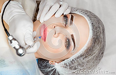 Healthy Spa. Young Beautiful Woman Having Permanent Makeup Tattoo on her Lips Stock Photo