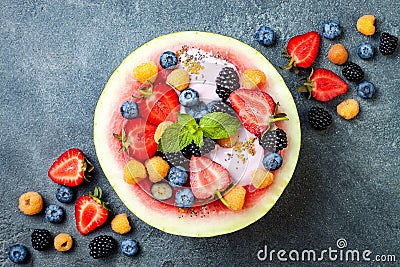 Healthy summer breakfast concept, fruit salad in carved watermelon. Watermelon bowl with yogurt, chia seeds, fresh berries Stock Photo