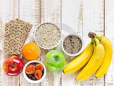 Healthy superfoods fiber source breakfast oats dried fruits apples bananas orange whole grain crackers milk thistle on white wood Stock Photo