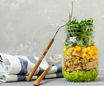 Healthy take-away lunch jar with Guacamole, corn, tofu, beans, arugula Stock Photo