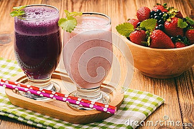 Healthy tasty milk cocktails with strawberries and blueberries on brown wooden background. Stock Photo