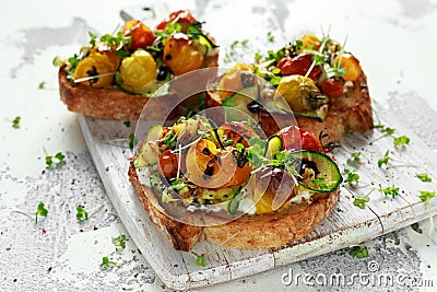 Healthy toasts with baked sweet cherry tomatoes and grilled zucchinin ribbons drizzled with balsamic vinegar Stock Photo