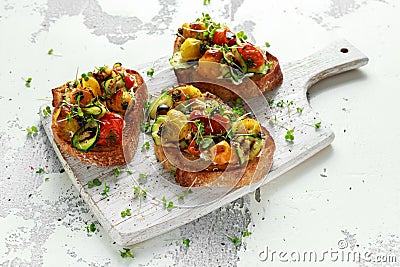 Healthy toasts with baked sweet cherry tomatoes and grilled zucchinin ribbons drizzled with balsamic vinegar Stock Photo