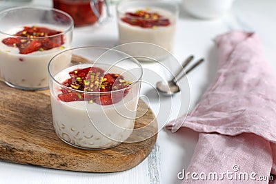 Healthy vegan dairy free dessert - tapioca pearls pudding with coconut milk and strawberry chia jam close up, served in glass jar Stock Photo