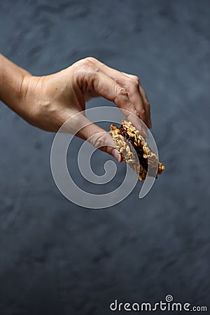 Healthy vegan sweets or dieting concept. Slender woman hand with homemade oatmeal breakfast cookie sandwich with dark chocolate on Stock Photo