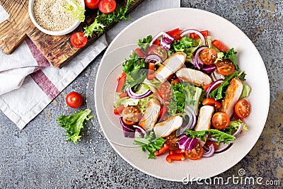 Healthy vegetable salad with grilled chicken breast, fresh lettuce, cherry tomatoes, red onion and pepper Stock Photo