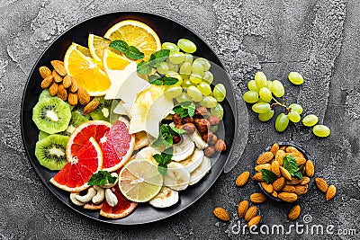 Healthy vegetarian bowl dish with fresh fruits and nuts. Plate with raw apple, orange, grapefruit, banana, kiwi, lemon, grape, alm Stock Photo