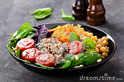 Healthy vegetarian dish with buckwheat and vegetable salad of chickpea, kale, carrot, fresh tomatoes, spinach leaves and pine nuts Stock Photo