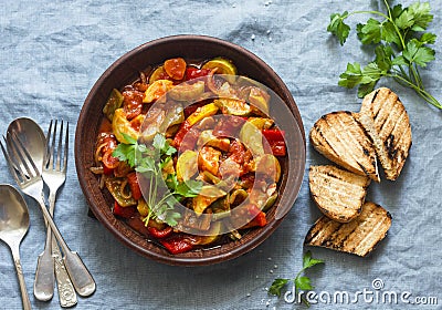 Healthy vegetarian lunch - stewed garden vegetables. Vegetable ratatouille and grilled bread. On a blue background Stock Photo