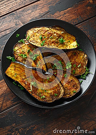 Healthy vegeterain Oven baked aubergines, Eggplant with parsley and herbs in a black plate Stock Photo