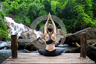 Healthy woman lifestyle balanced practicing meditate and zen energy yoga on the bridge in morning the waterfall in nature forest. Stock Photo