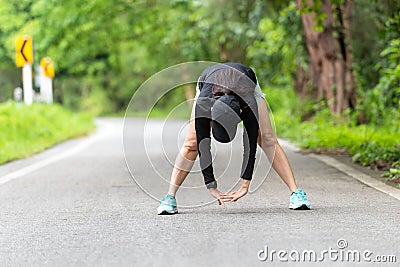 Healthy woman warming down stretching her legs and looking away in the road outdoor. Asian runner woman workout Stock Photo