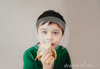 Healthy young boy eating banana, Happy kid having breakfast, Cute Child looking at camera with smiling face Stock Photo
