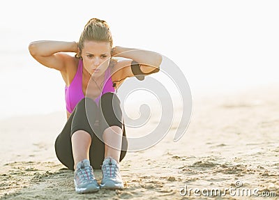 Healthy young woman doing abdominal crunch on beach Stock Photo