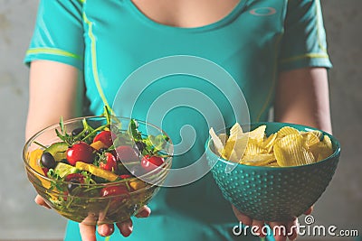 Healthy young woman looking at healthy and unhealthy food, trying to make the right choice Stock Photo