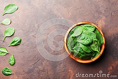 Heap of baby spinach leaves in wooden bowl on rustic stone table top view. Organic healthy food. Stock Photo