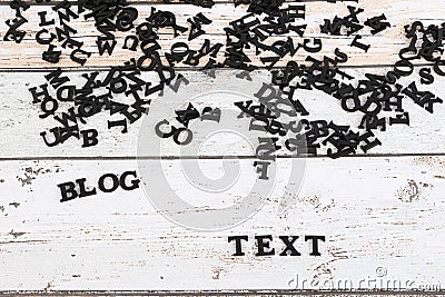 A heap of black wooden letters are lying on the table and create the words blog and text Stock Photo