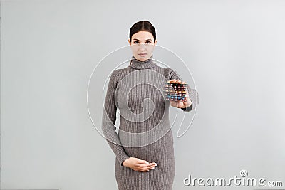 Heap of blisters of pills in pregnant woman`s hand at colorful background with copy space. Healthcare and treatment during Stock Photo