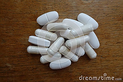 Heap of caplets of calcium citrate and capsules of magnesium citrate on wood Stock Photo