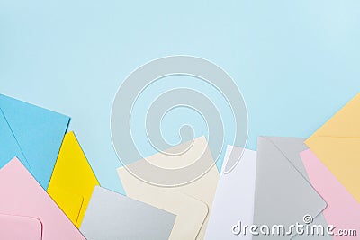 Heap of colorful envelopes on blue working desk top view. Mockup for business mail, blogging and office correspondence. Flat lay. Stock Photo