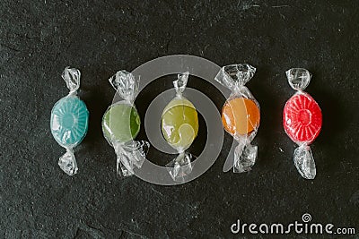 Heap of colorful fruity candies on black slate background. Close up view of different multicolored candies. Stock Photo