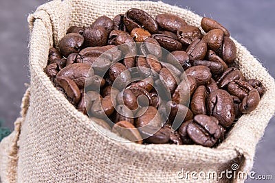 Heap of dark roasted fragrant coffee beans in jute bag Stock Photo