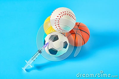 Heap of different balls near syringe on blue background. Concept of doping in professional sport Stock Photo