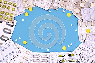 Heap of different pills and capsules in blister packs on a blue background top-down frame copy space. Coronavirus. Stock Photo