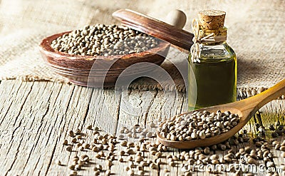 Heap of dried organic hemp seeds or cannabis plant seeds in spoon and bowl with glass of hemp seed oil Stock Photo