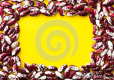 Heap of dry uncooked red and white speckled beans arranged in frame on bright yellow background. Creative food poster Stock Photo
