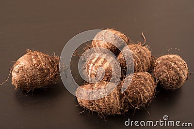 Heap of fresh taro roots (colocasia) on black background. Stock Photo