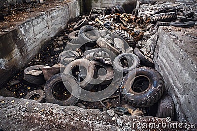 Heap of old car junk tires, used truck rubbish wheels, industrial garbage in abandoned factory Stock Photo